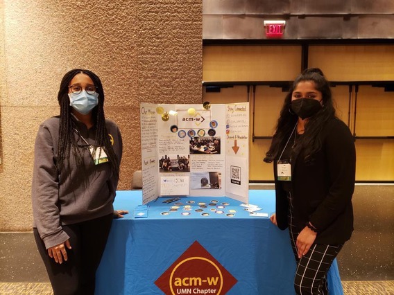 Group photo showing two ACM-W officers standing in front of an ACM-W table at the CSE DEI leadership showcase